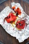 Tin foil with two roasted red peppers on it