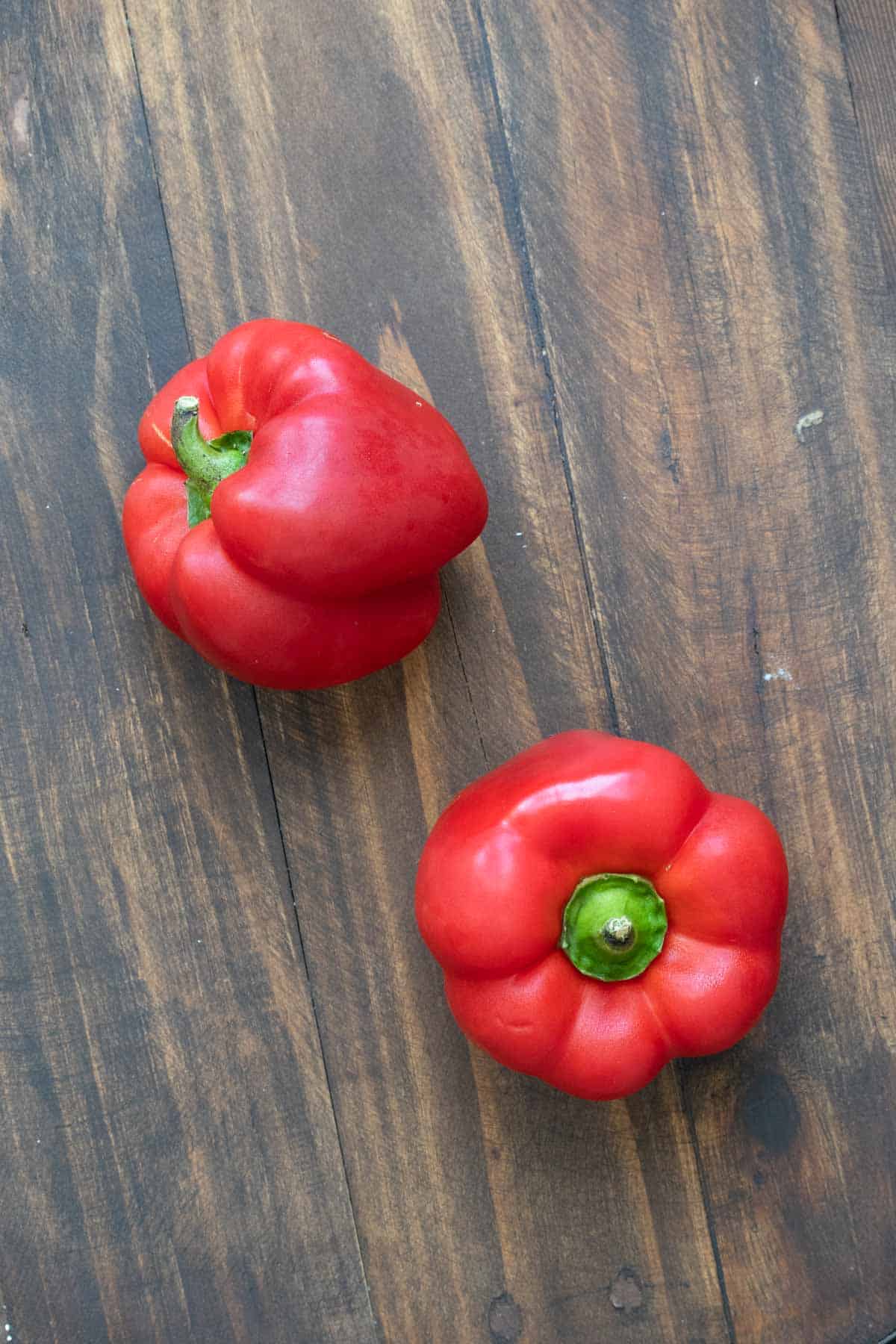 Two red peppers on a wooden table