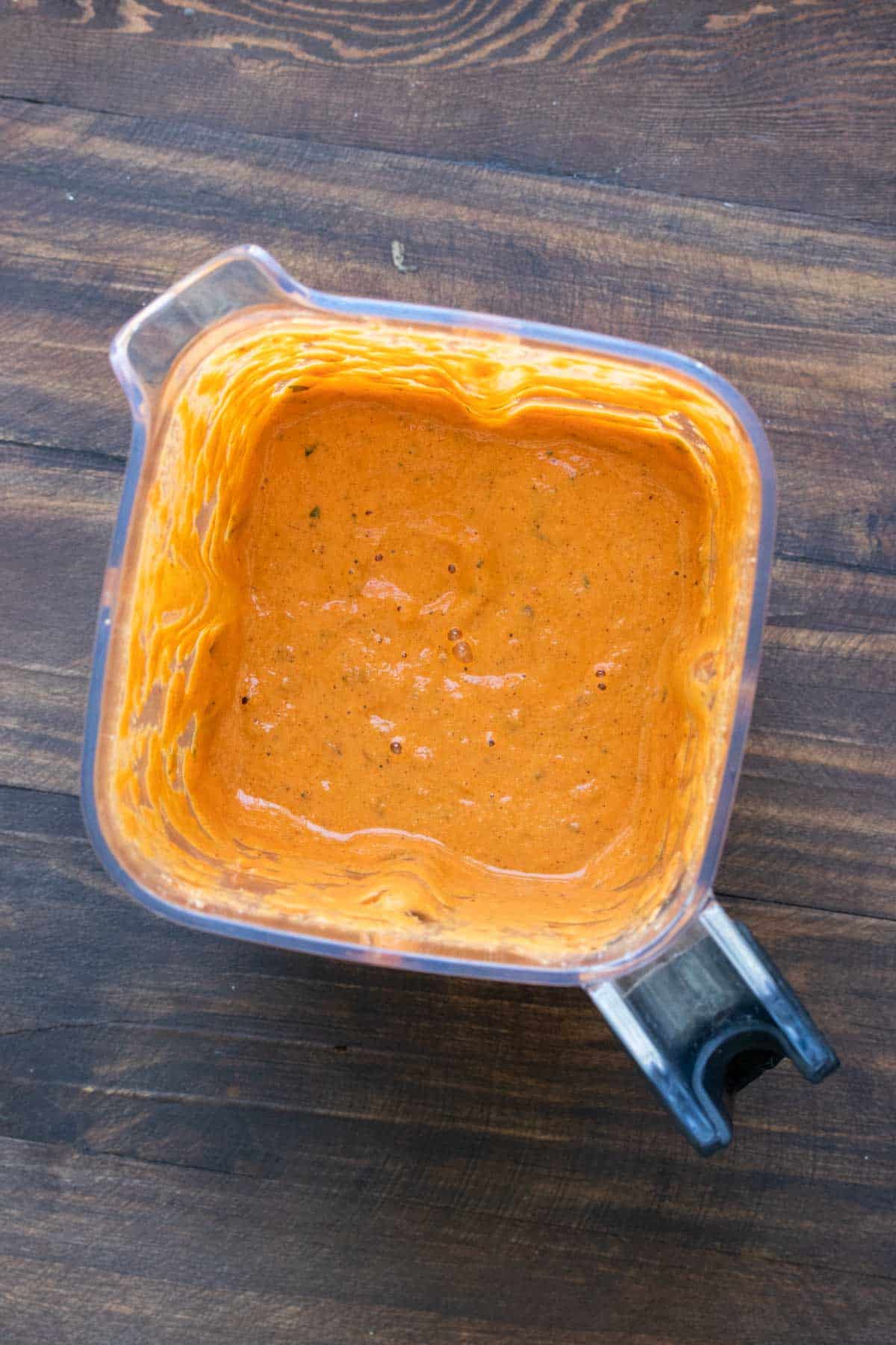 Top view of blender with a creamy red pepper sauce
