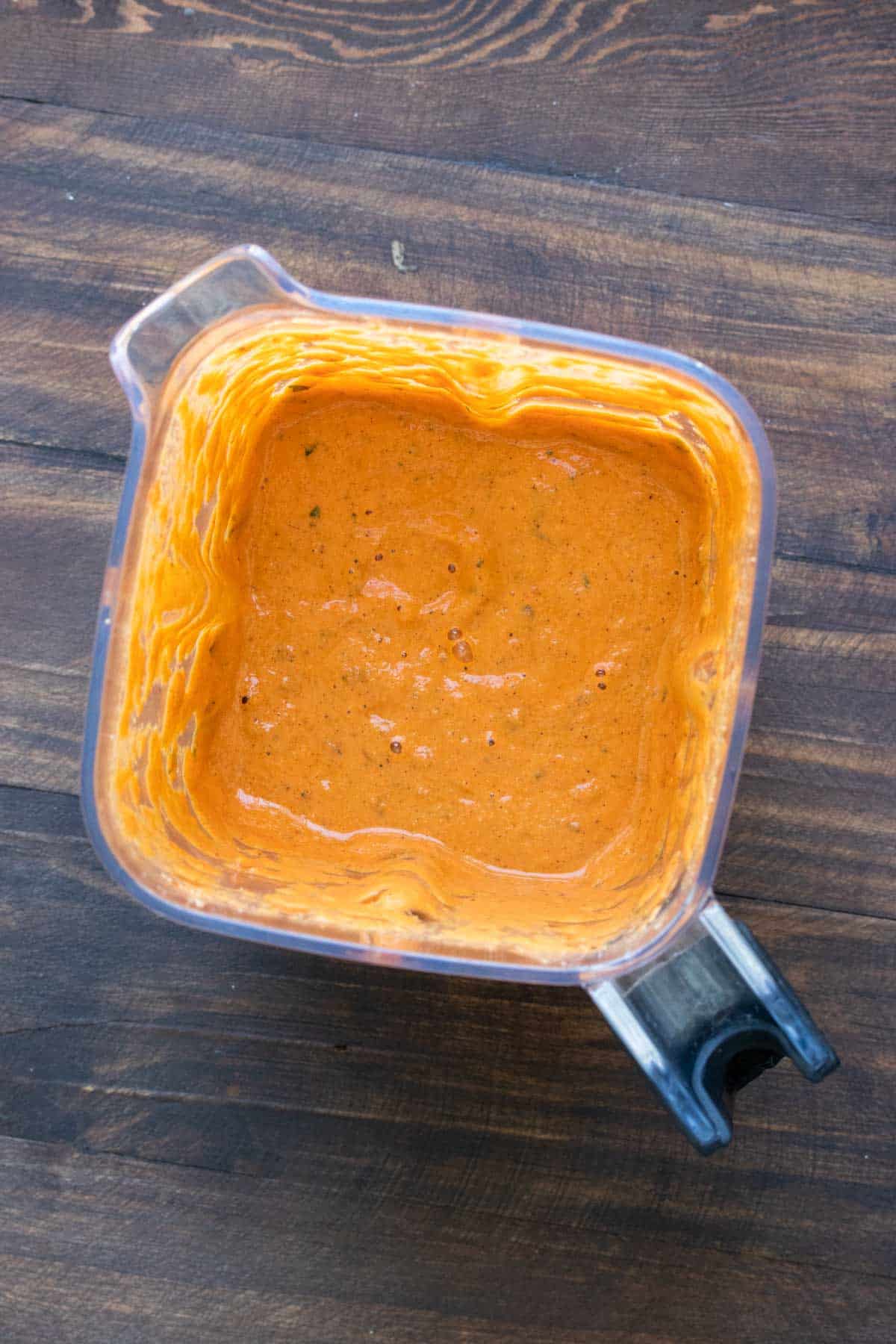 Top view of blender with a creamy red pepper sauce