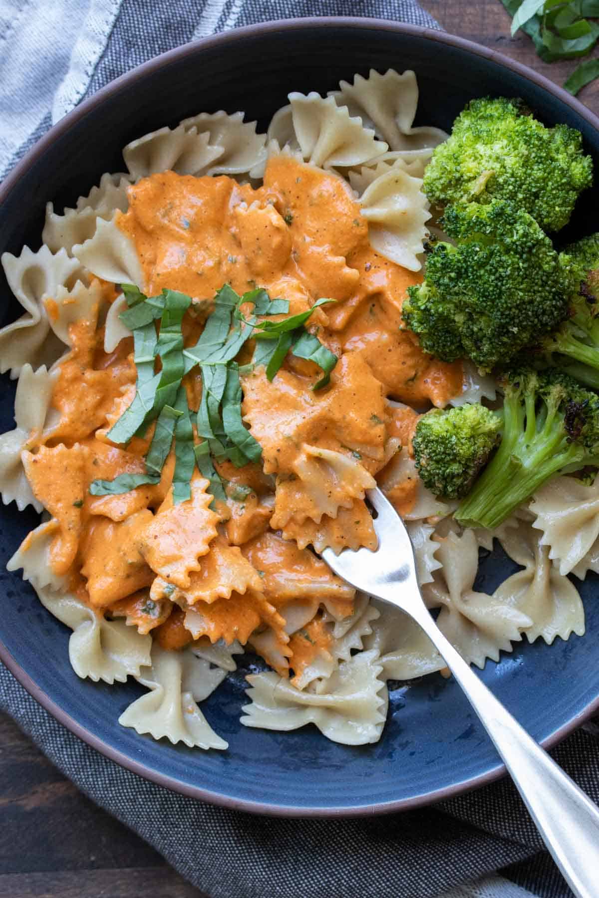 Fork getting a bite of roasted red pepper sauce covered pasta