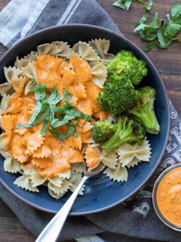 Bowl of bow tie pasta covered in creamy red pepper sauce