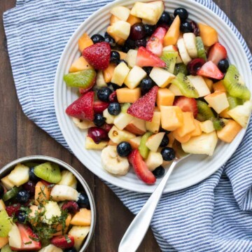 Fruit salad in a bowl next to a plate of it