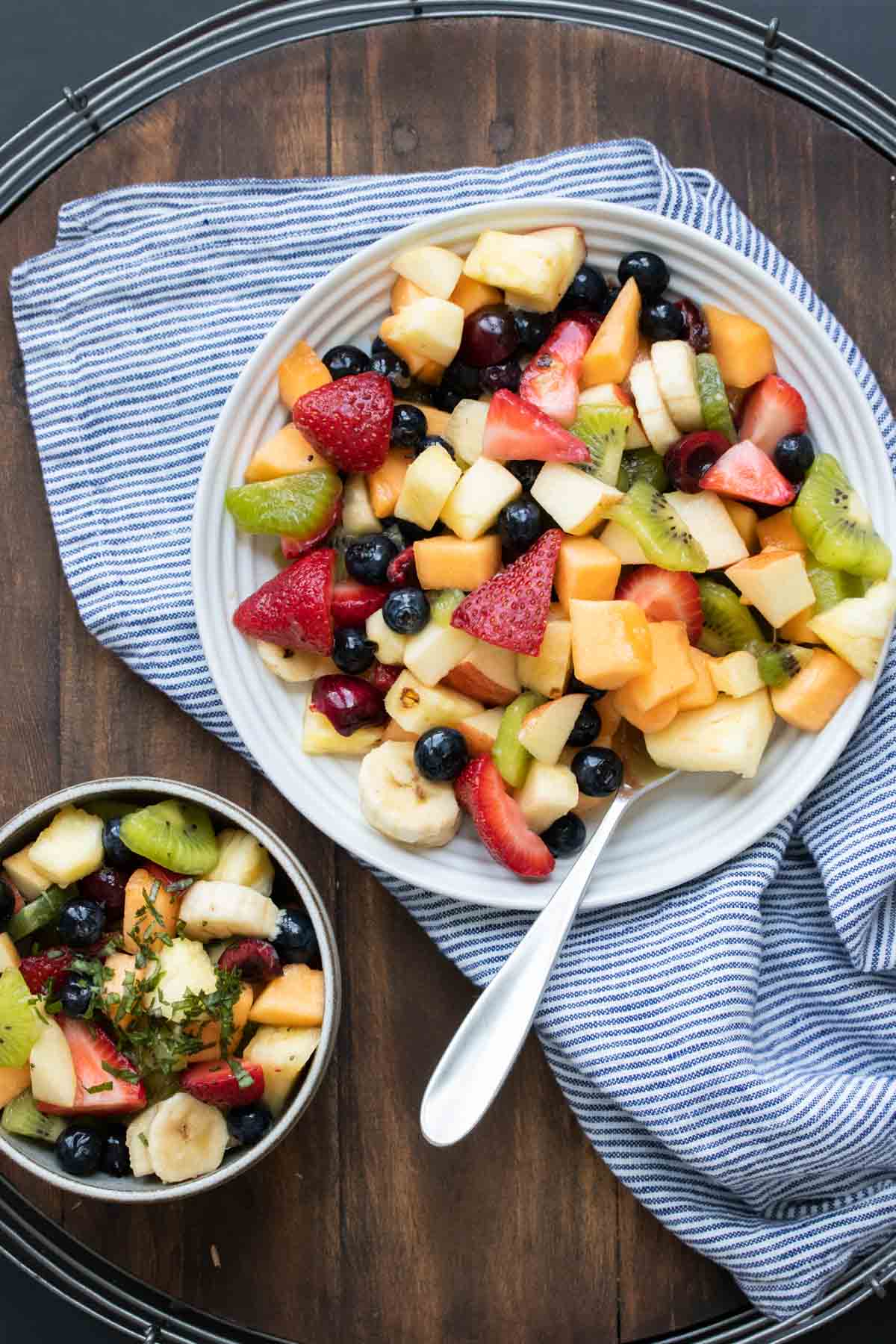 Fruit salad in a bowl next to a plate of it