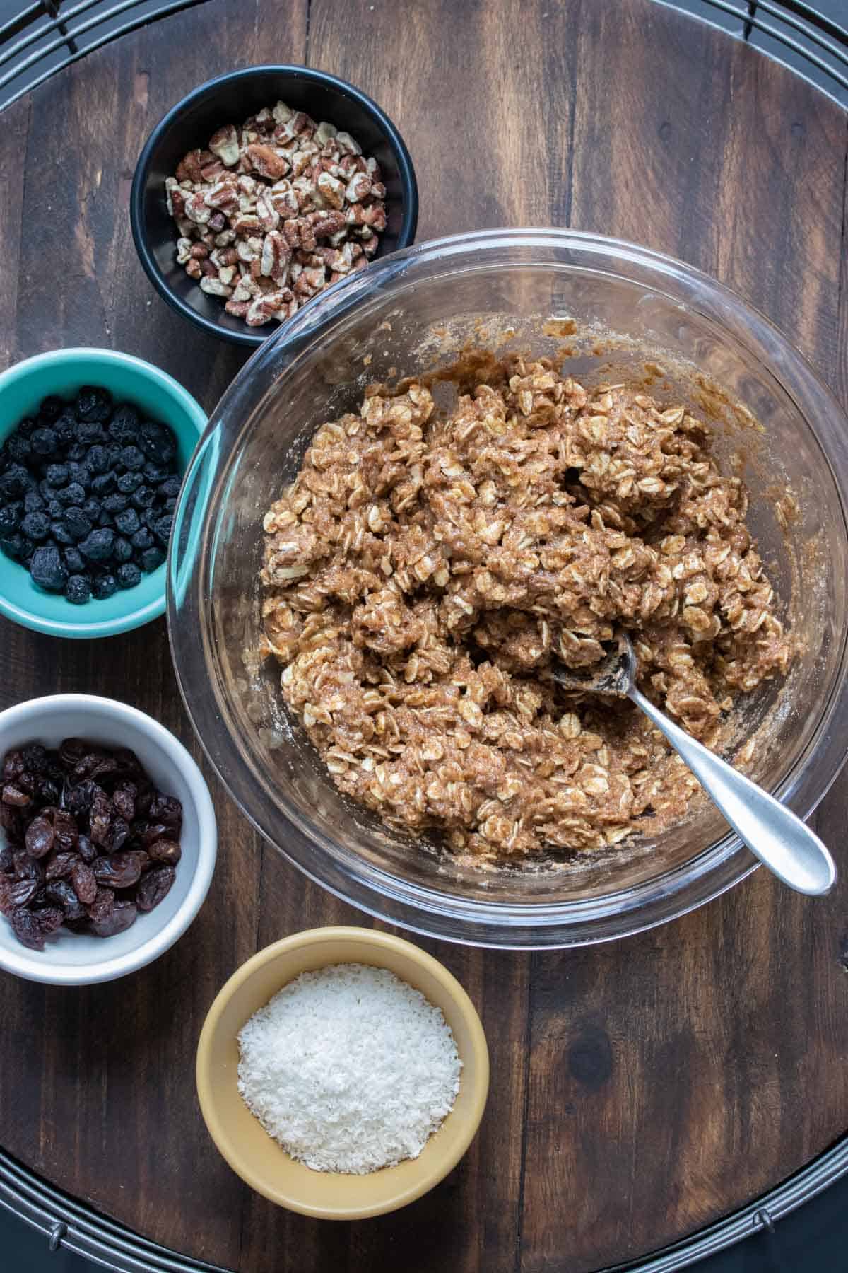 Glass bowl with oat cookie batter next to bowls of toppings