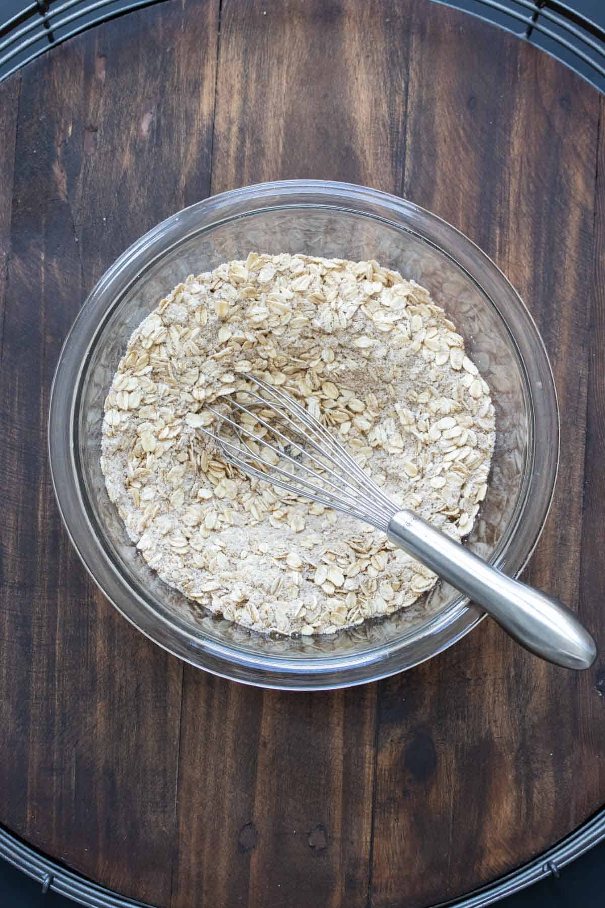 Glass bowl of flour and oats with a whisk in it