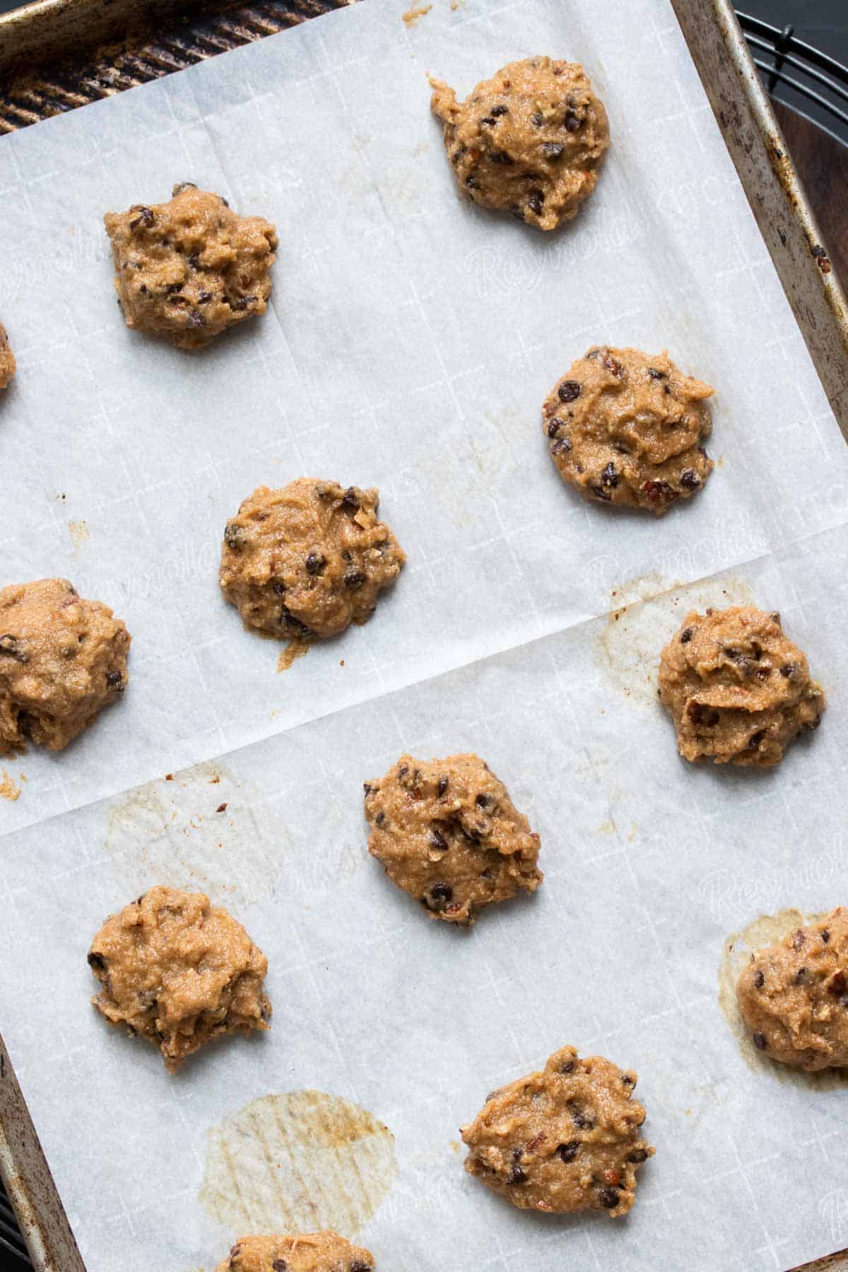 Drops of cookie dough on a parchment lined baking sheet