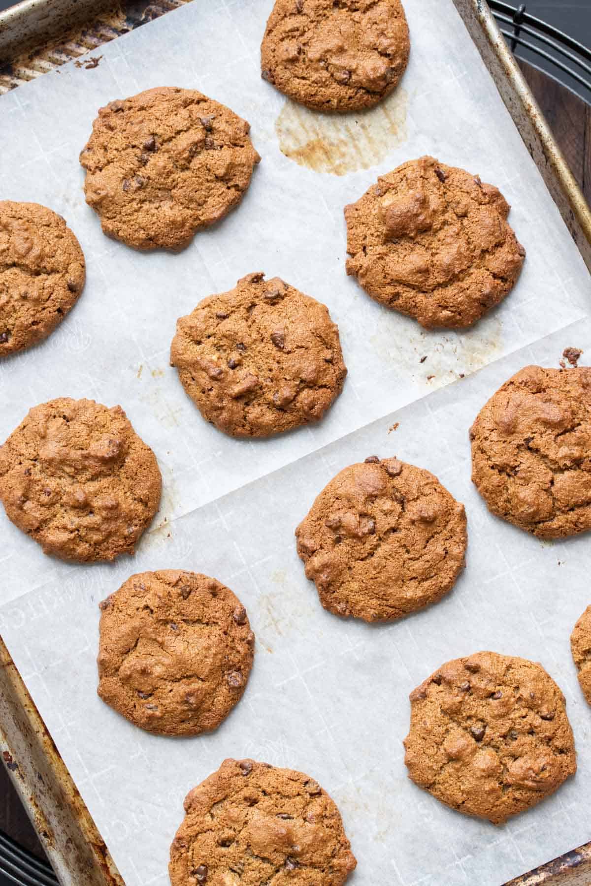 Baked chocolate chip cookies on a parchment lined baking sheet