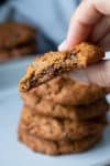 Hand holding a half eaten chocolate chip cookie close to the camera