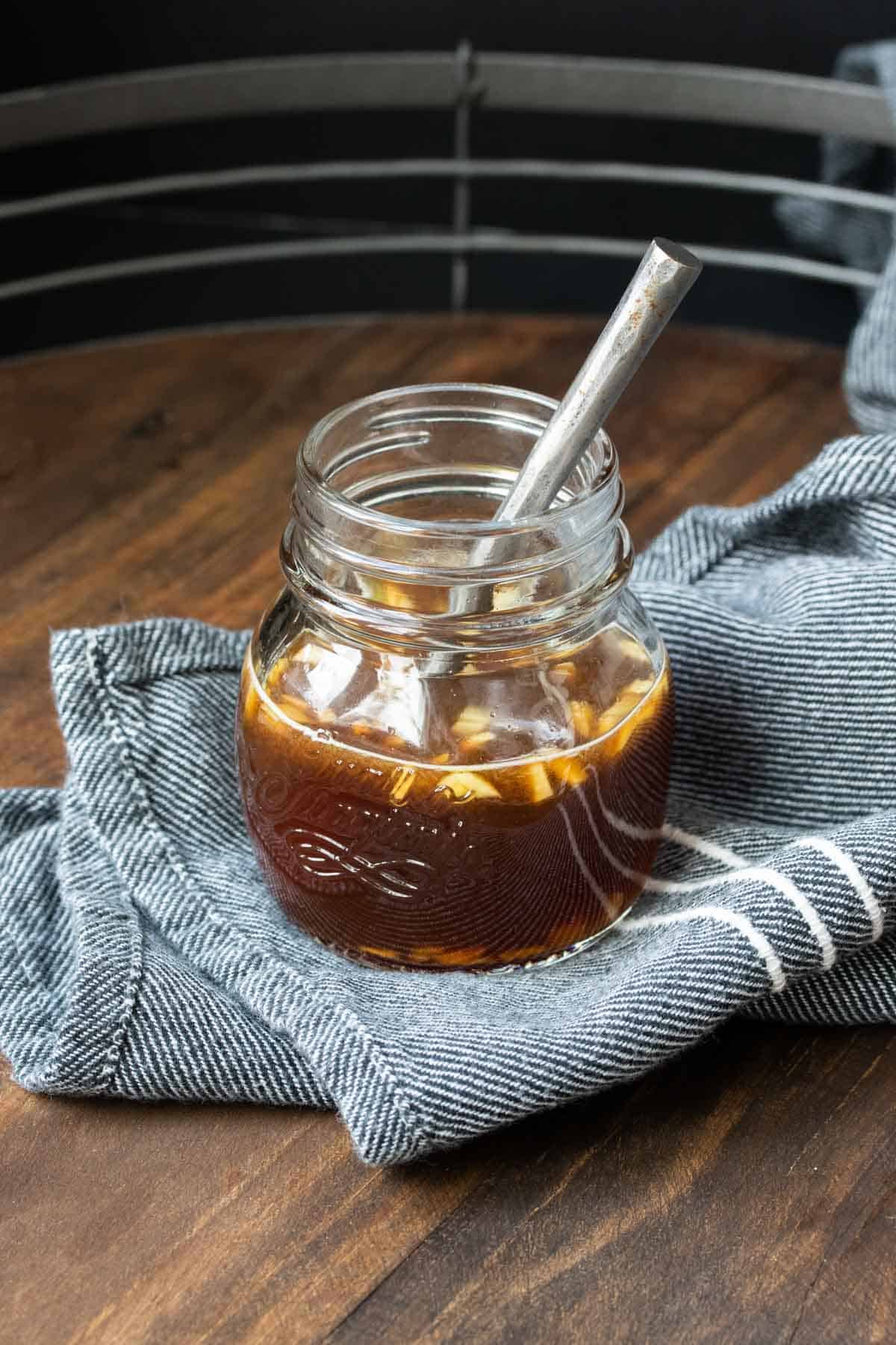 Glass jar with brown liquid inside and a spoon in it