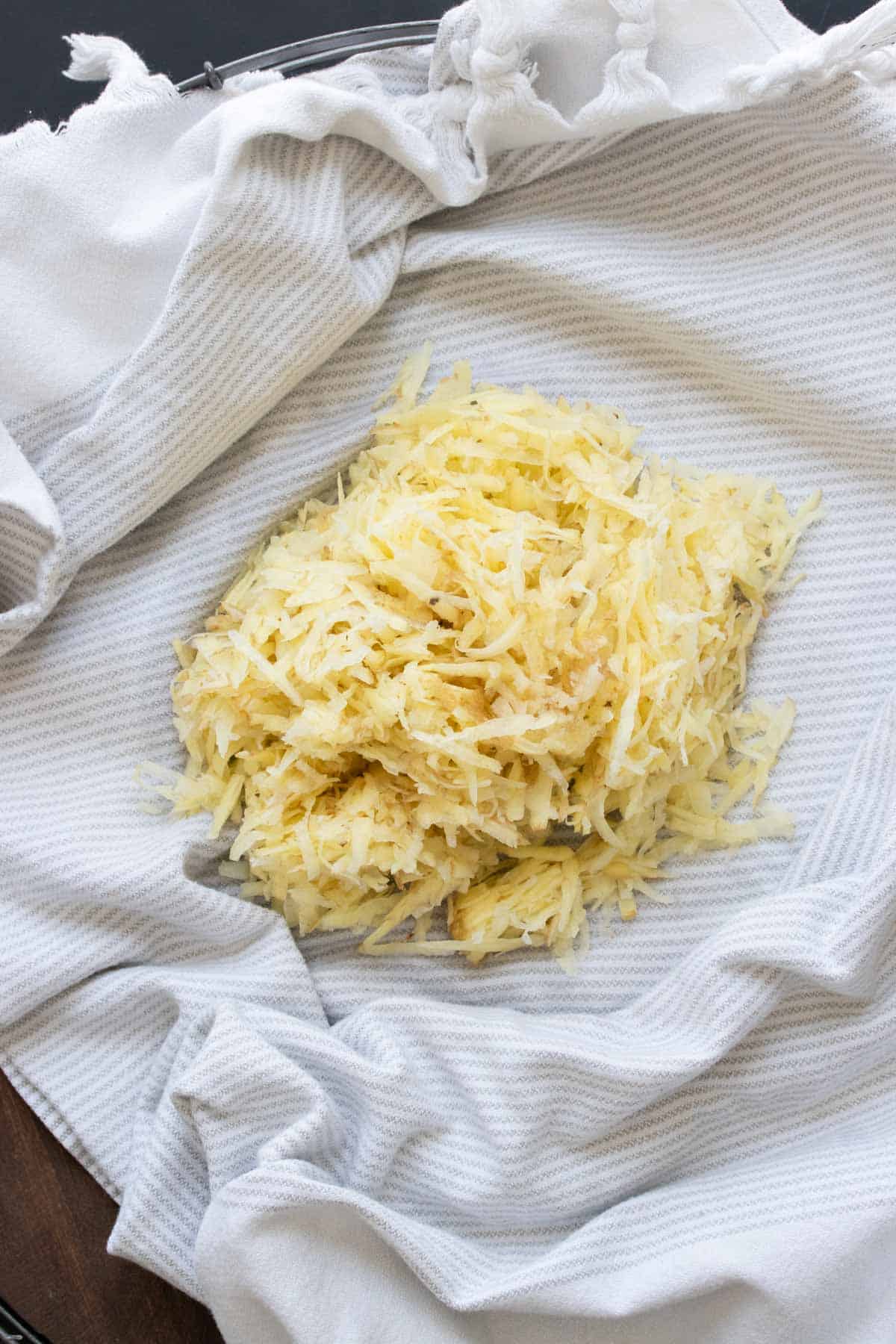 A pile of raw shredded potato in a kitchen towel