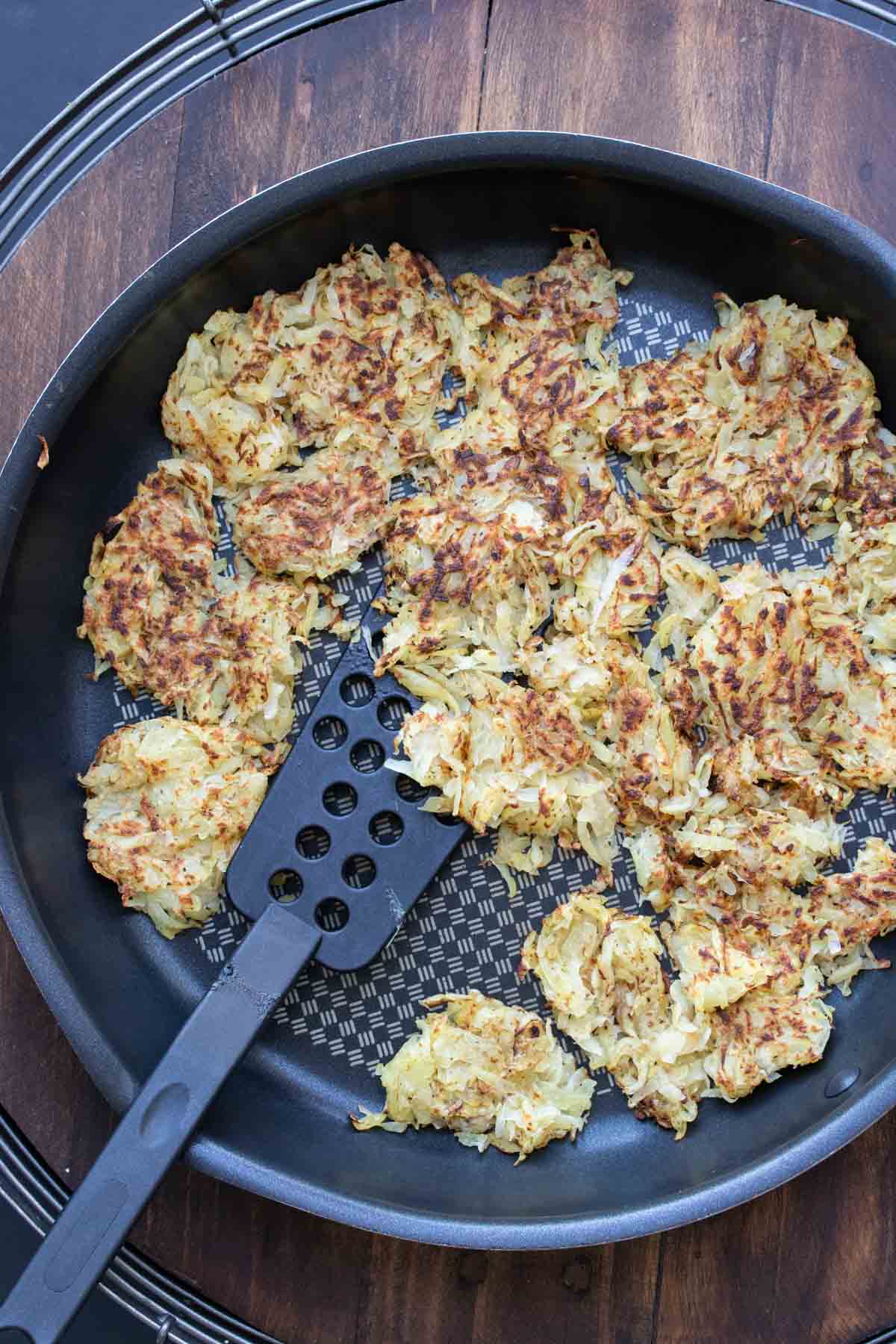 Spatula cooking hashbrowns in a pan