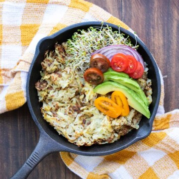 Skillet with cooked hashbrowns and pile of veggies