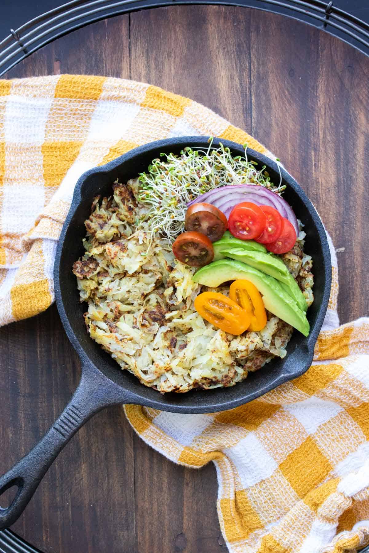 Skillet with cooked hashbrowns and pile of veggies