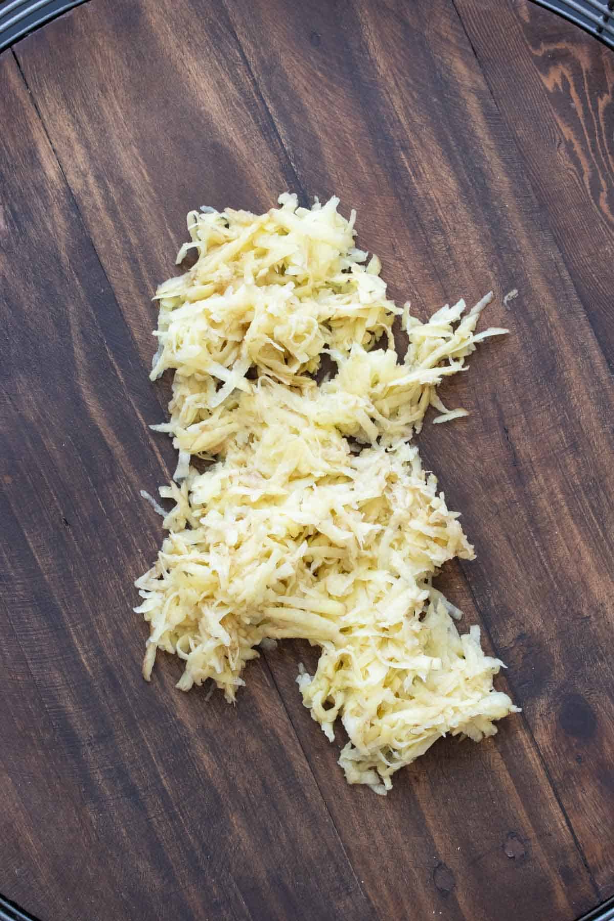 Shredded raw potato pile on a wooden table