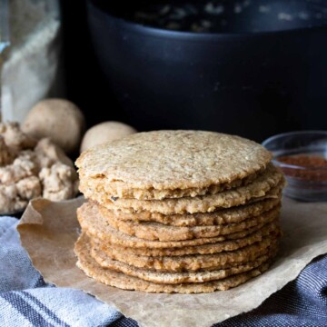 Pile of cooked homemade corn tortillas on a piece of parchment