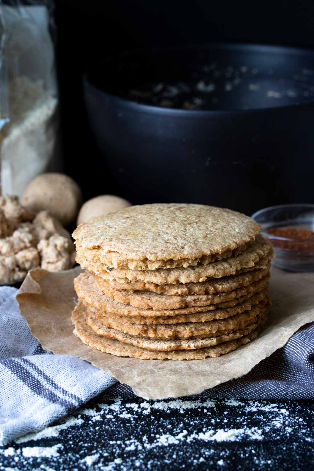 Pile of cooked homemade corn tortillas on a piece of parchment