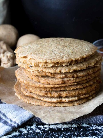 A stack of homemade cooked corn tortillas on a piece of parchment paper