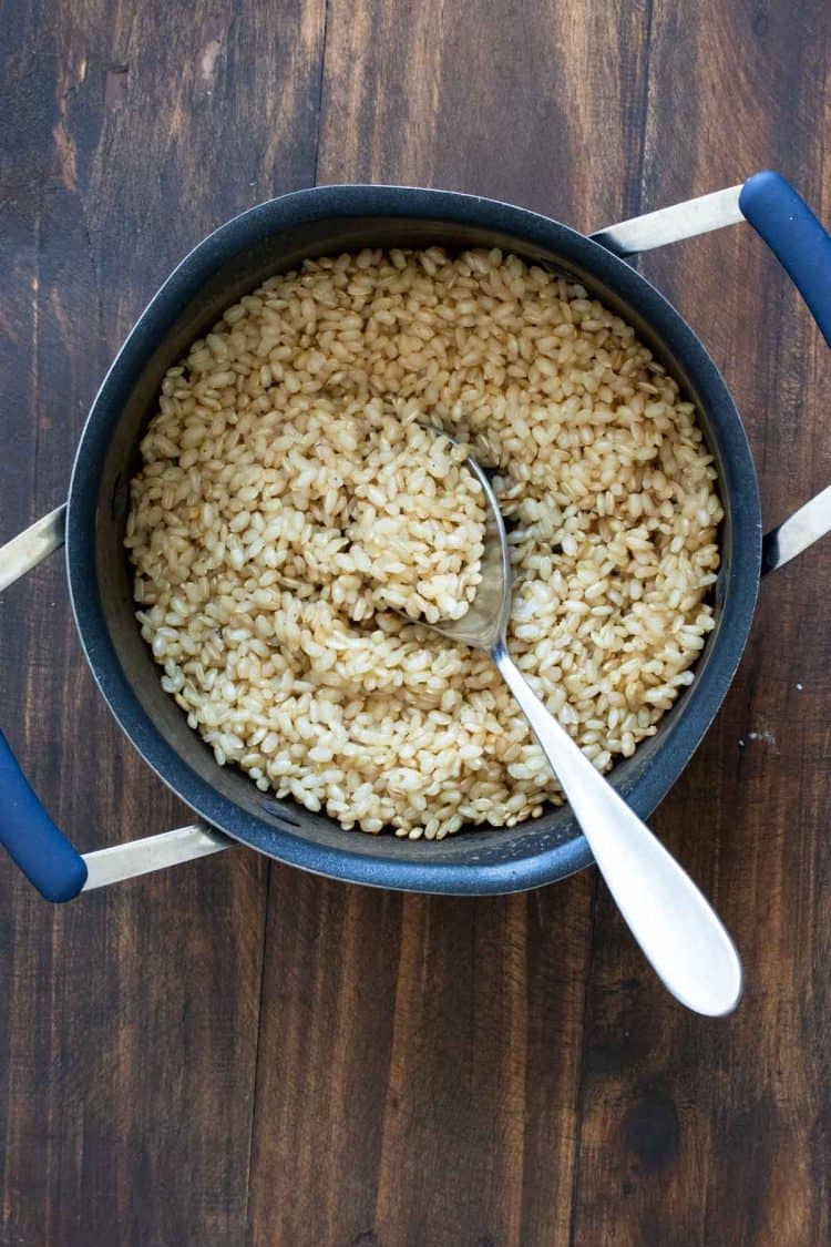 Spoon scooping brown rice out of a pot