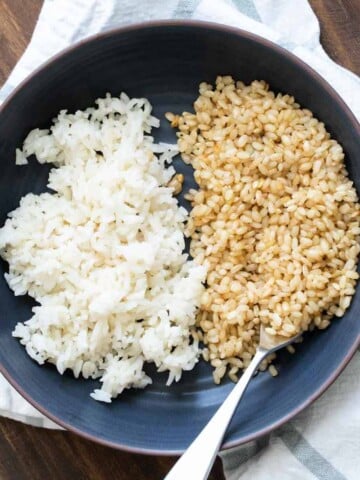 Black bowl filled half with white rice and half with brown rice