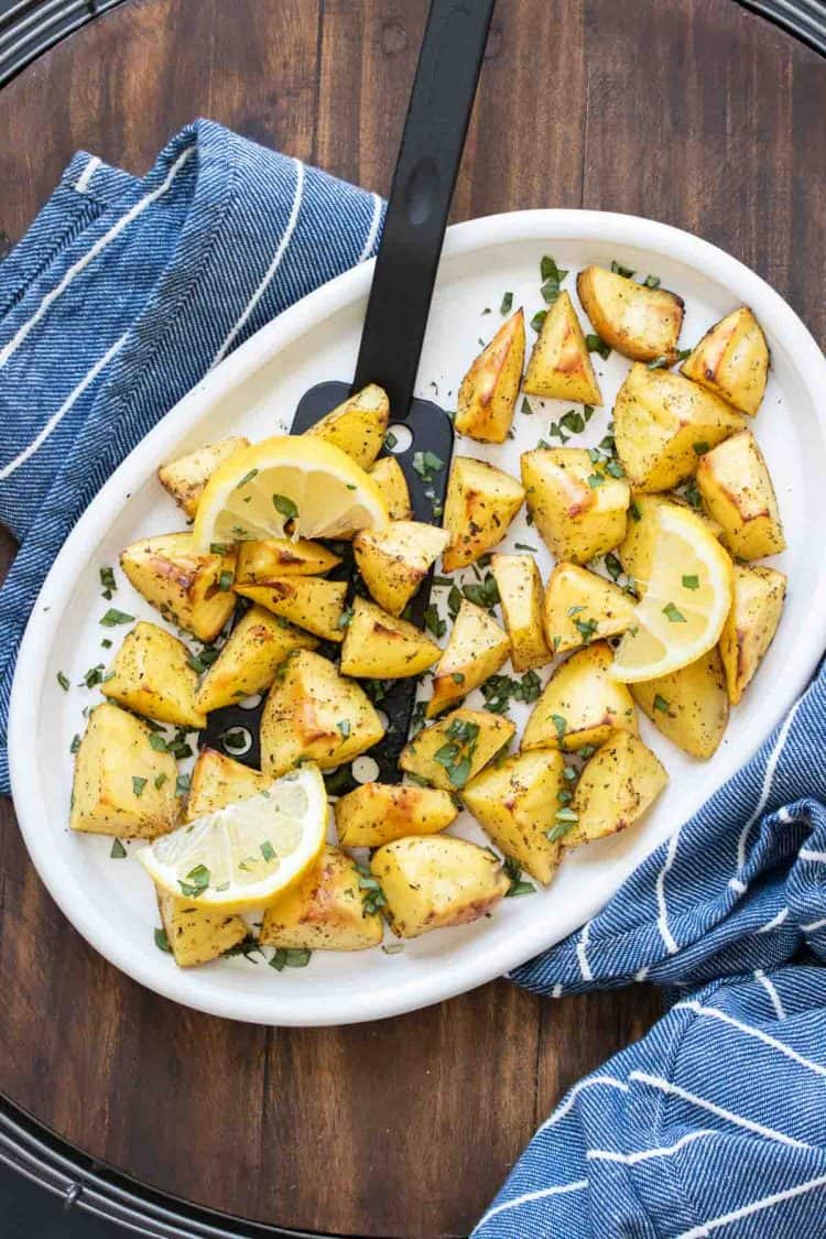 White platter with oven roasted pieces of potato topped with oregano.