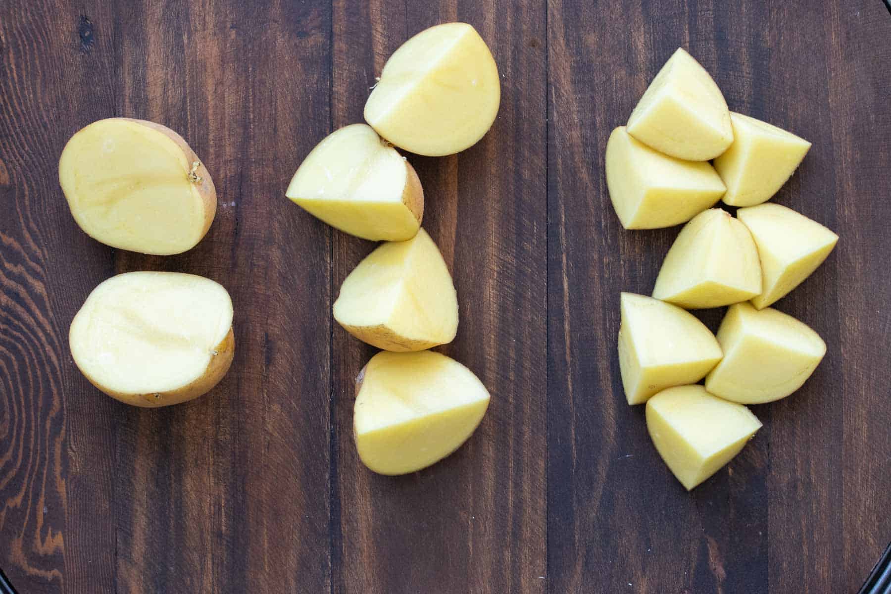 Piles of cut potatoes on a wooden table top.