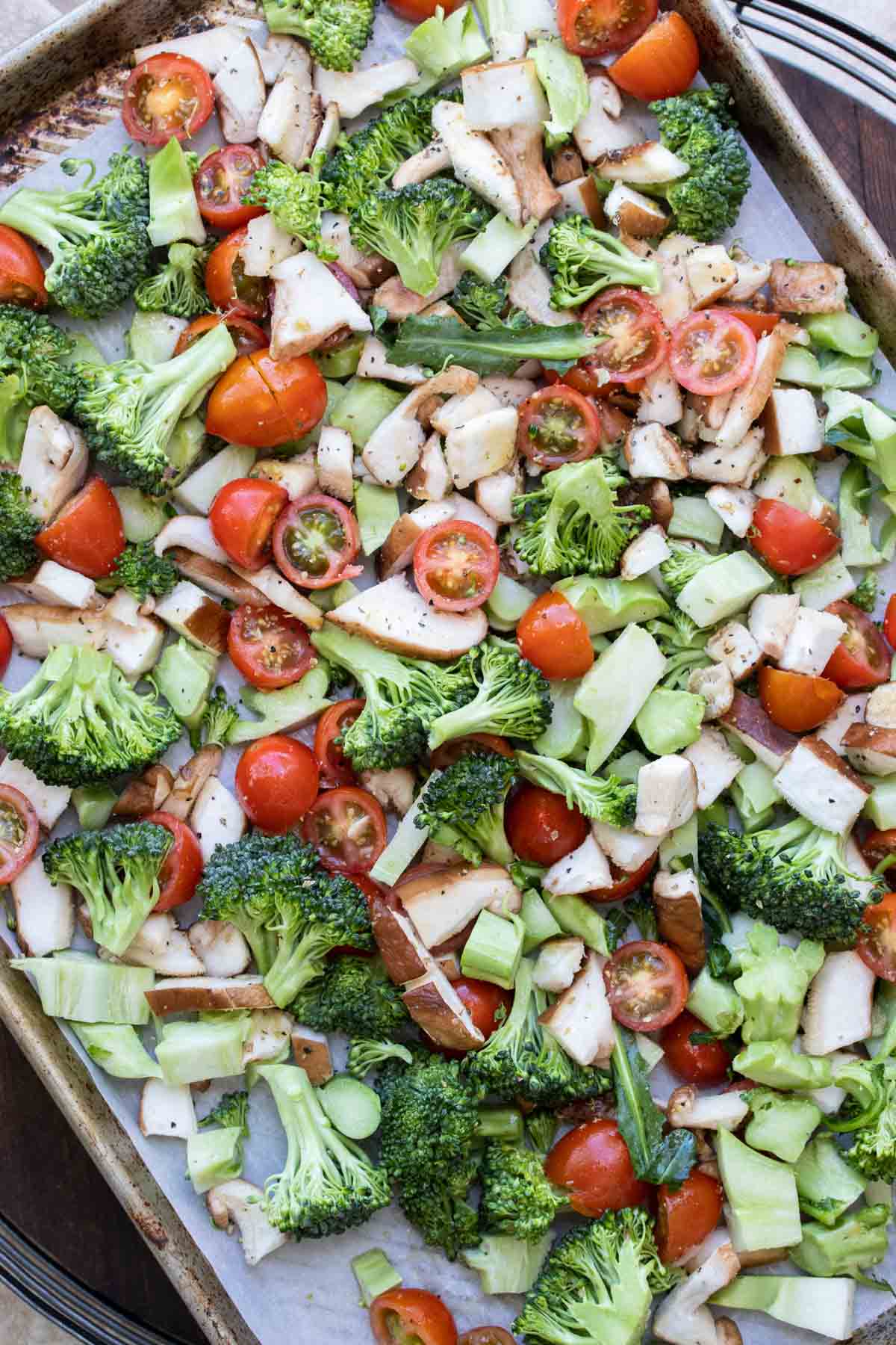 Baking sheet covered with different cut veggies.