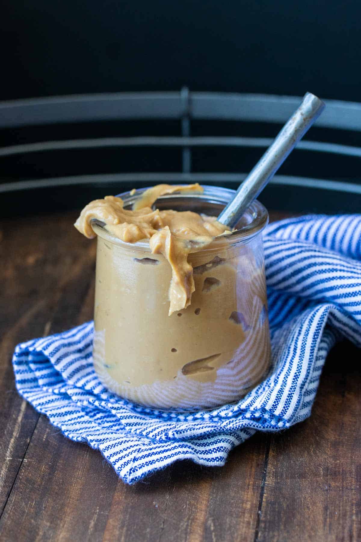 Glass jar with a thick brown sauce and a spoon