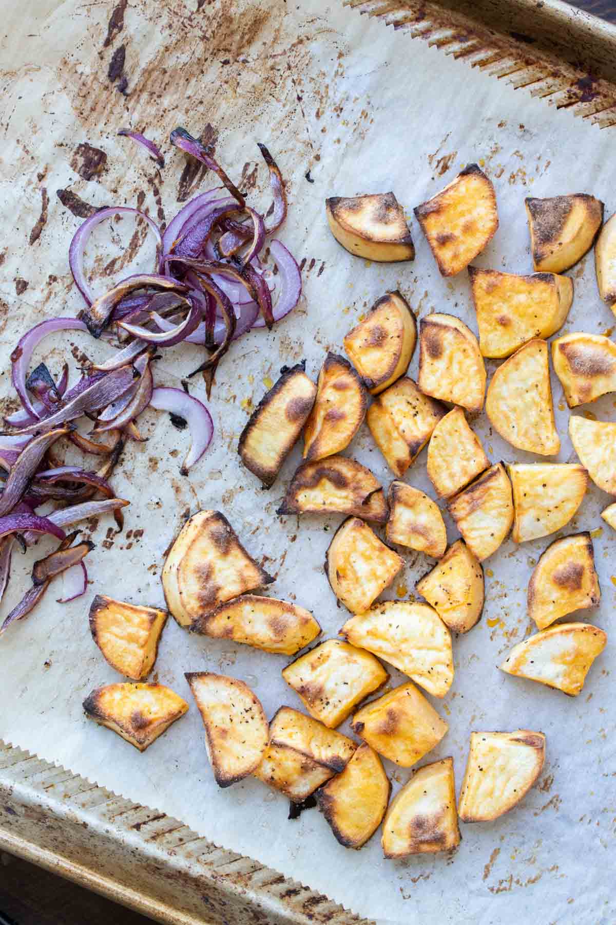 Roasted sweet potato and red onion on a piece of parchment paper