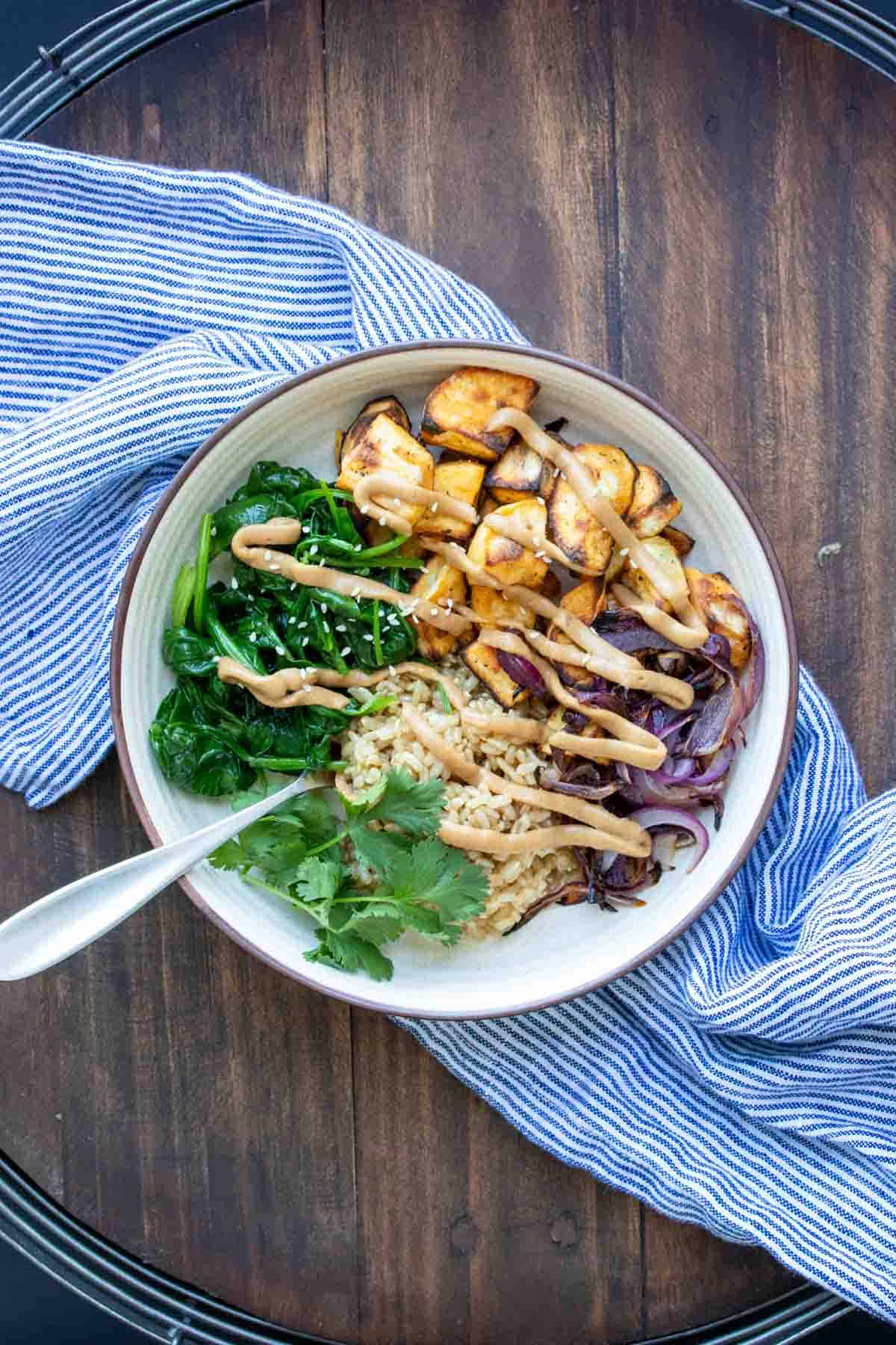 Fork in a cream bowl with rice, potatoes, spinach, onion and sauce