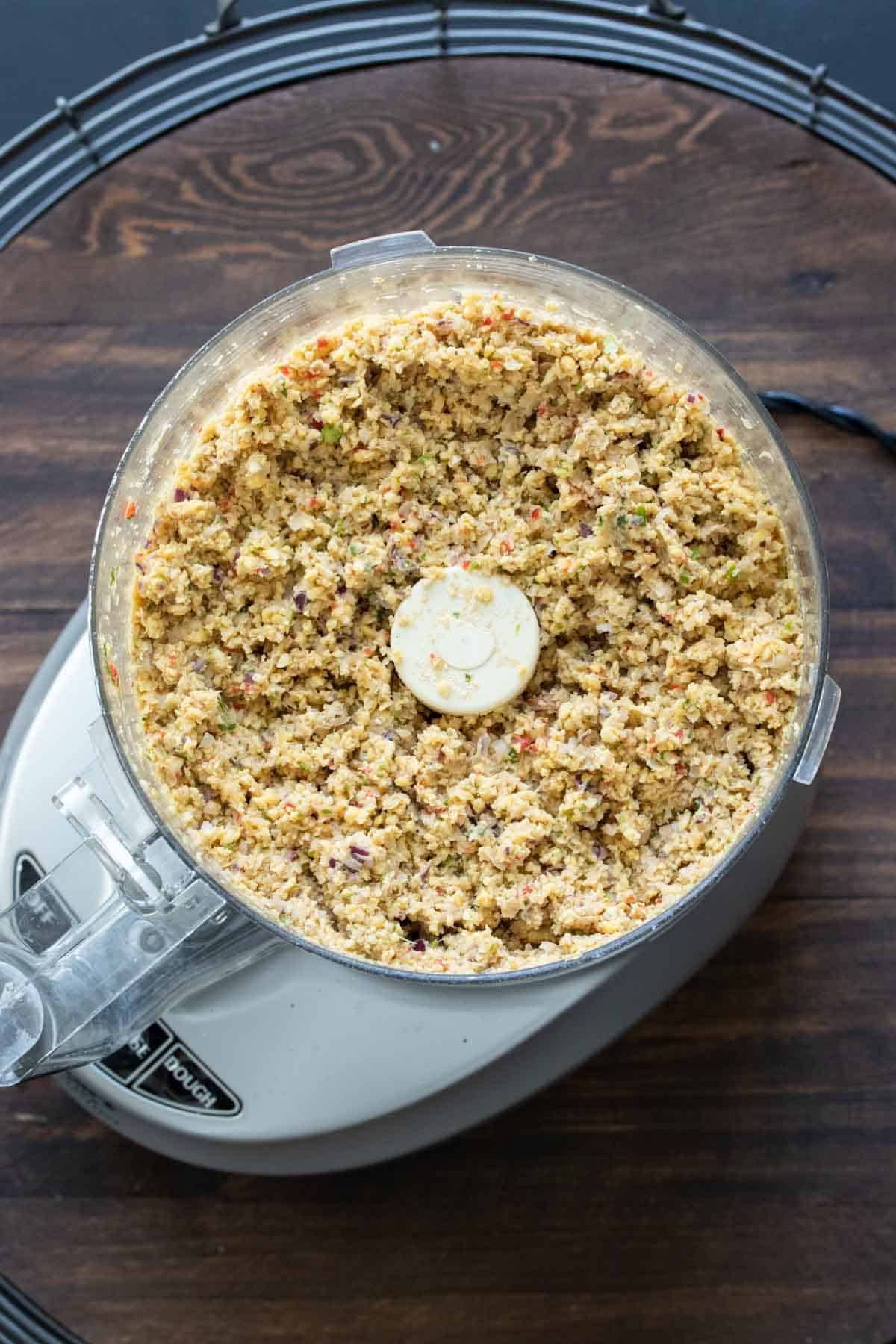 Top view of a food processor with falafel burger mixture in it.