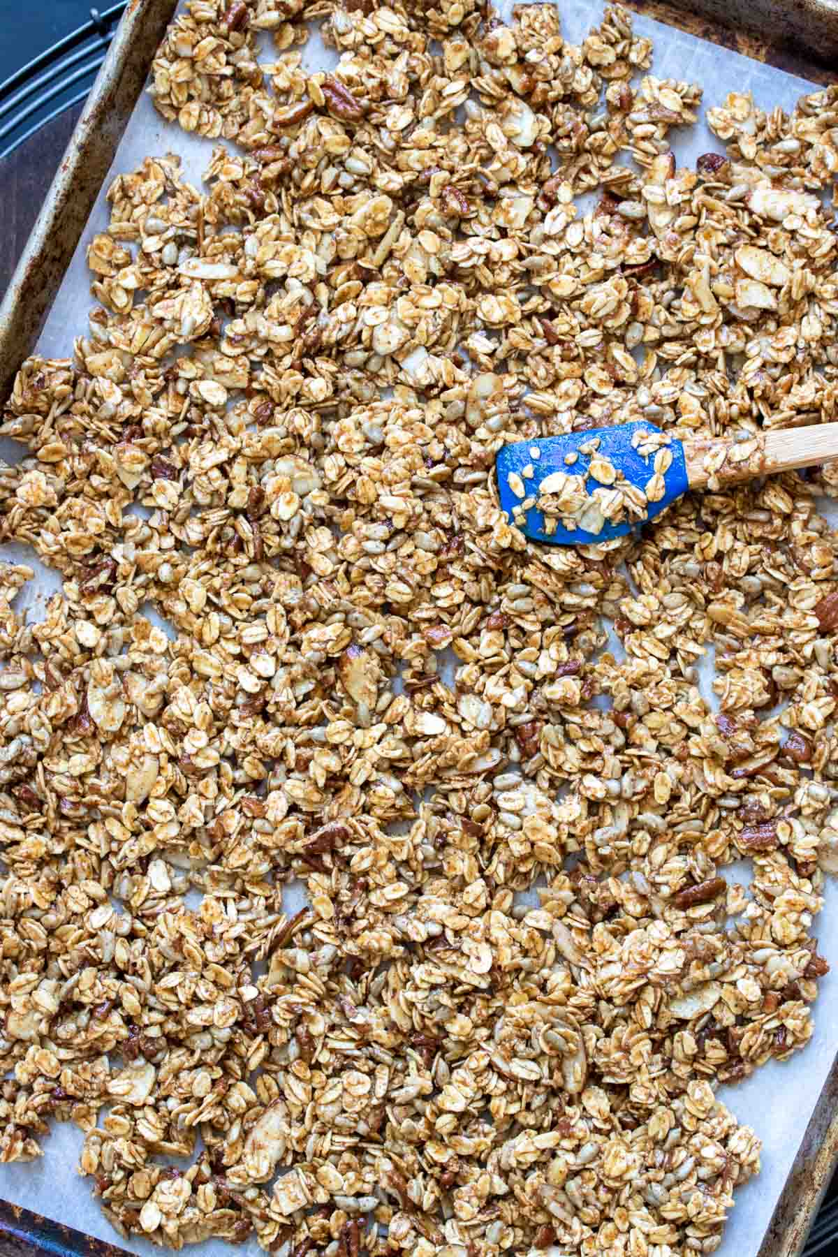 Spatula spreading unbaked homemade granola on a pan