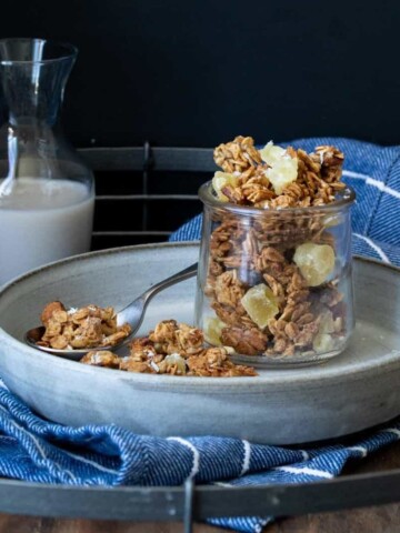 Glass jar filled with granola next to a pile of it