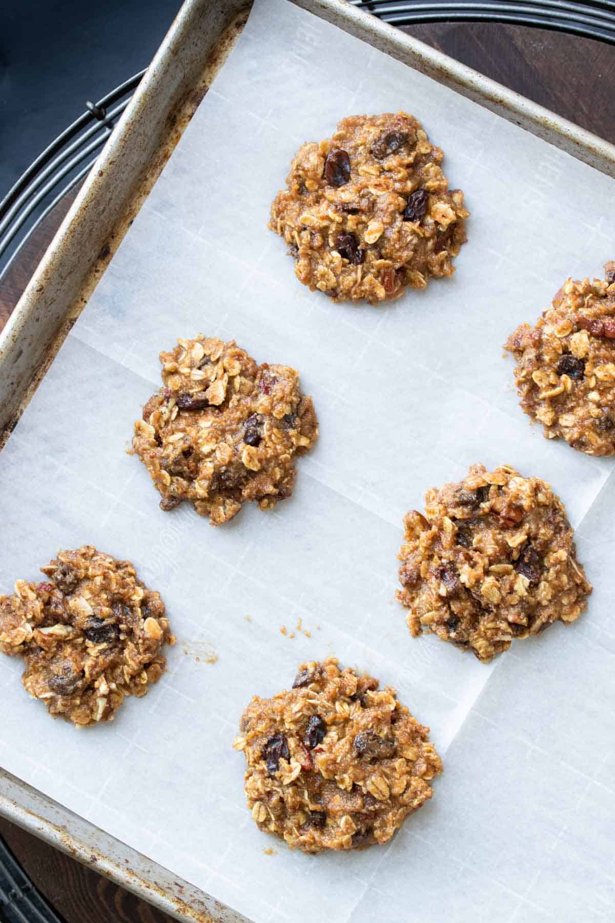 Spoonfuls of raw oatmeal raisin cookie dough on parchment paper