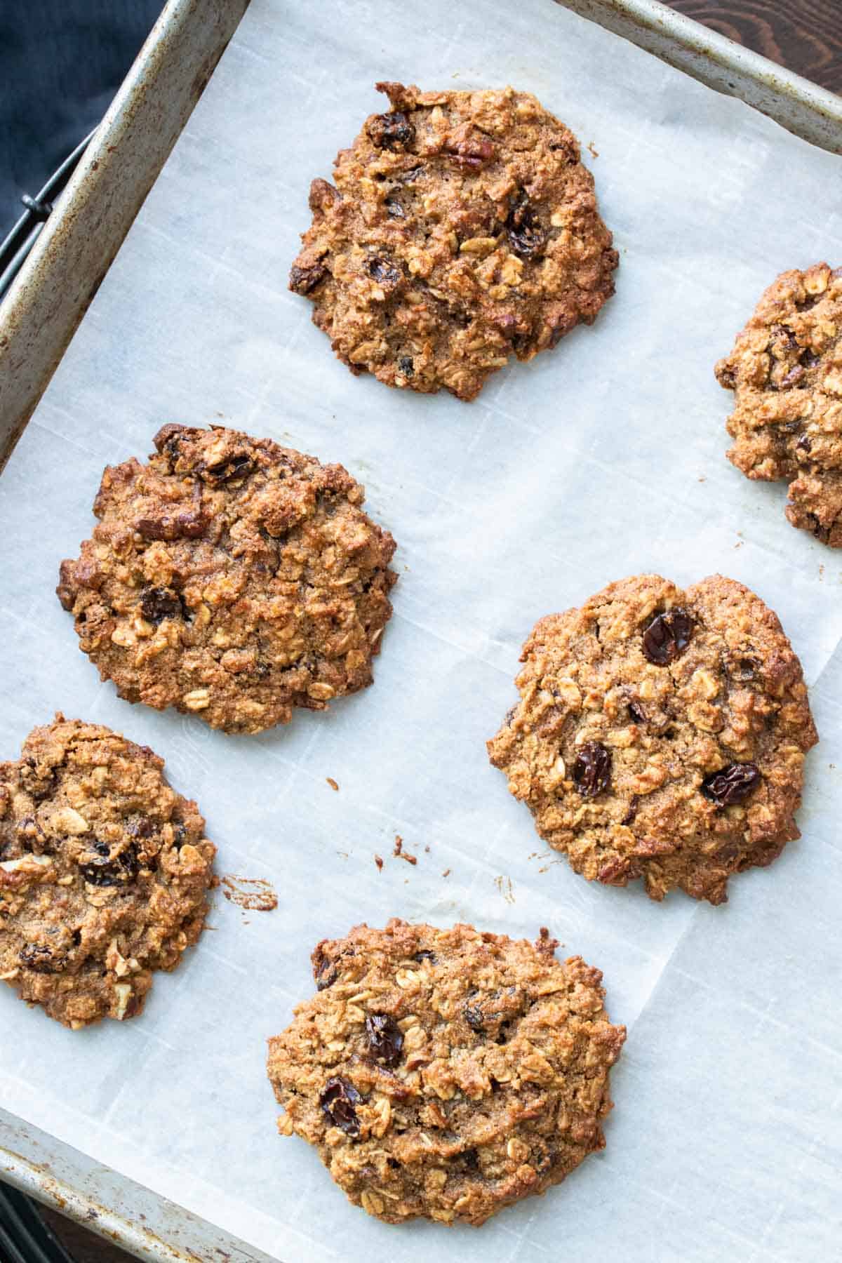 Parchment paper on a cookie sheet with baked oatmeal raisin cookies