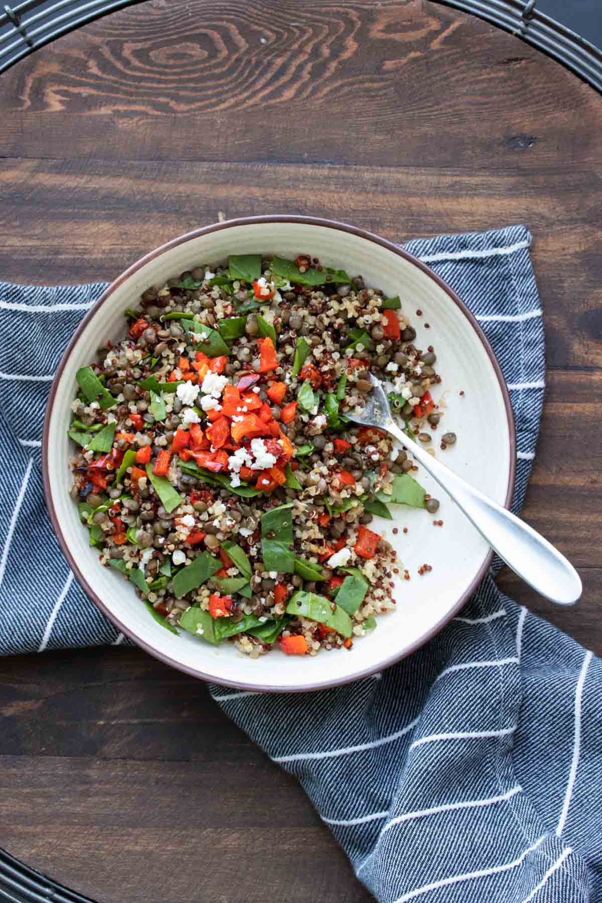 White bowl with lentil quinoa salad and red peppers