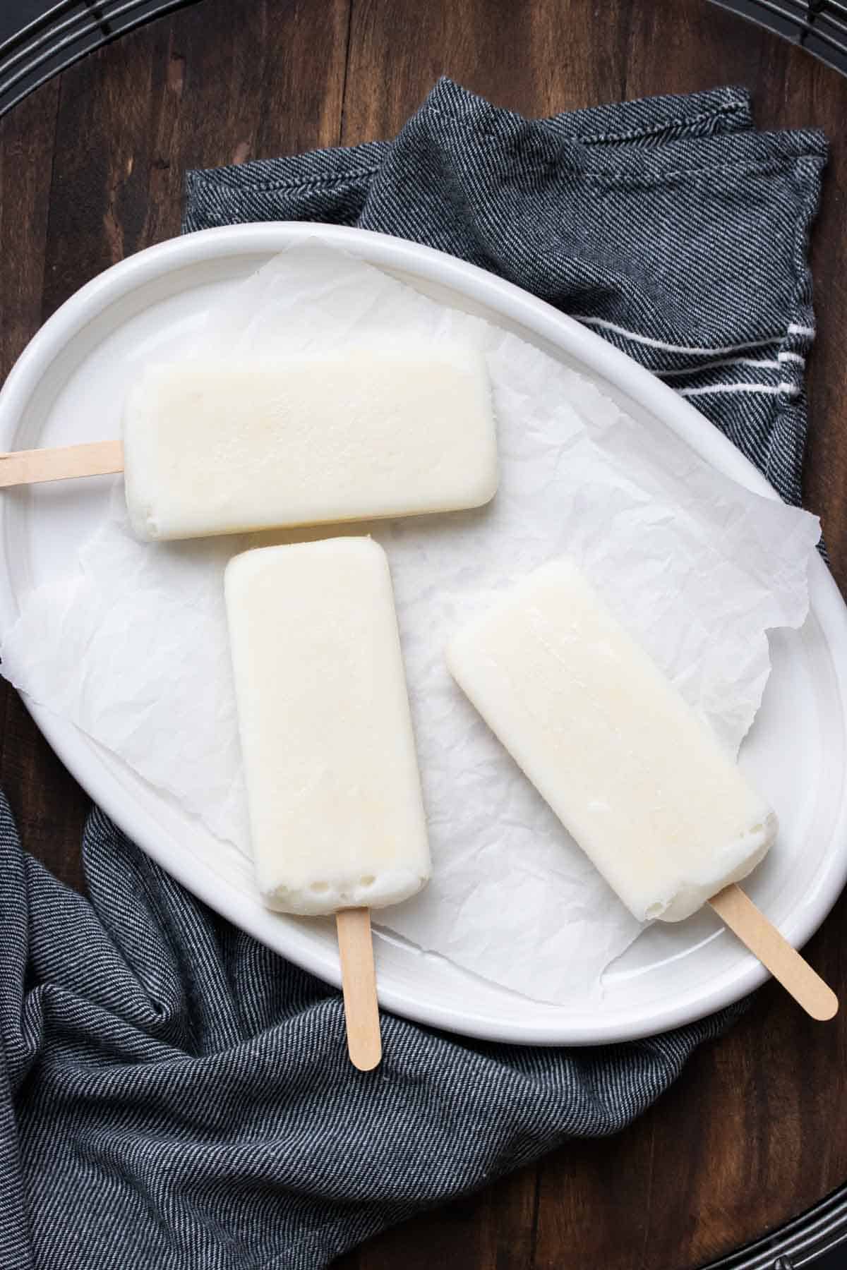 Plain white popsicles laying on a white platter