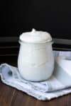 A glass jar sitting on a blue and white striped towel filled with a whipped cream.