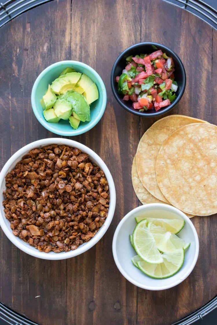 Bowls with taco ingredients on a table with corn tortillas