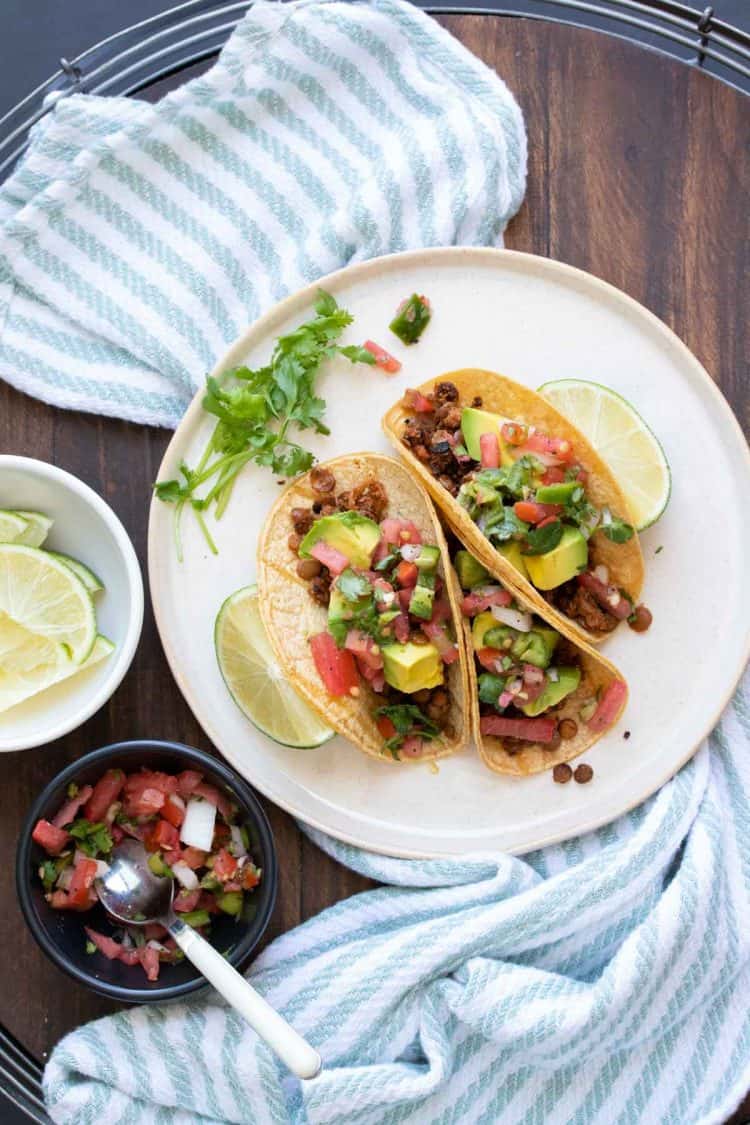 White plate with tacos filled with lentil taco meat and toppings