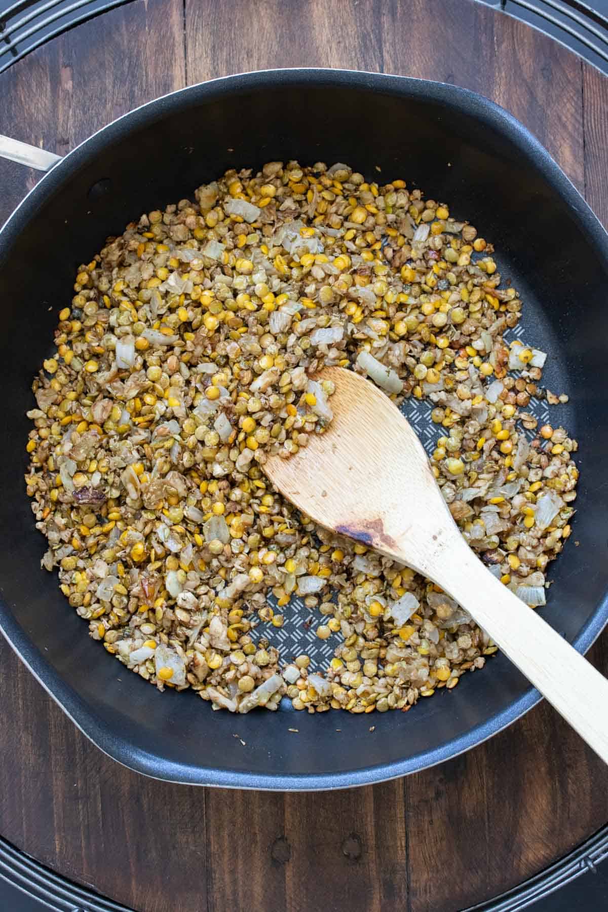 Lentils and onions being sautéed in a pan