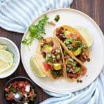 White plate with three lentil walnut meat and salsa tacos on it