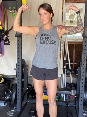 Photo of a woman with arm tattoos wearing workout gear flexing