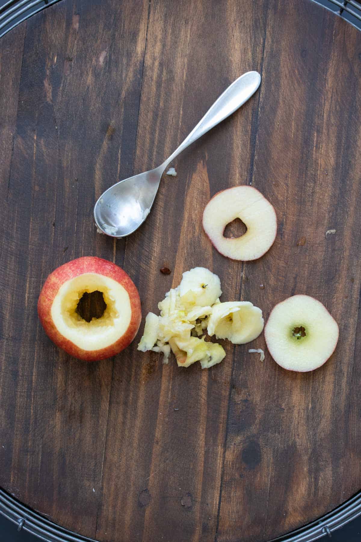 Spoon taking the core out of a raw apple
