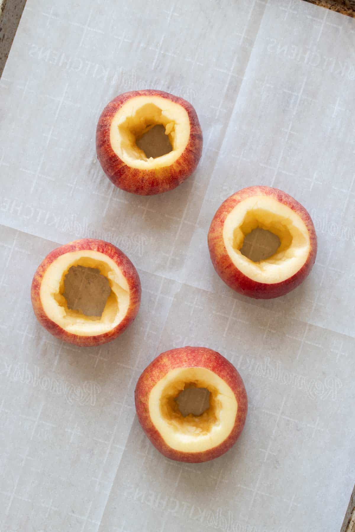 Four cored apples on a piece of parchment ready to be filled