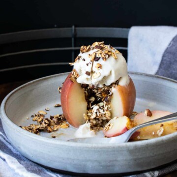 A baked apple with a piece out filled with oats on a grey plate