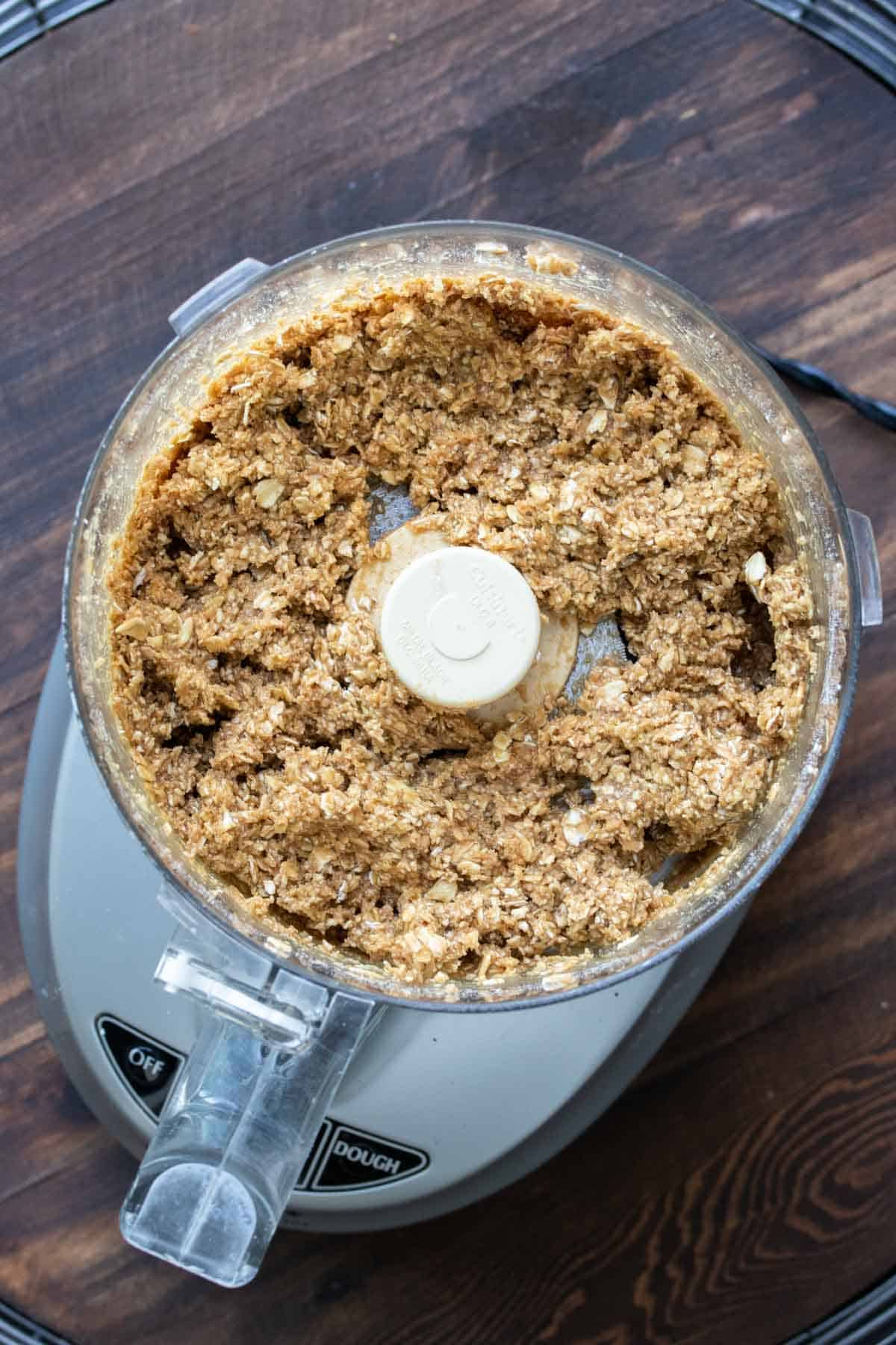 Top view of food processor with oat based crumble in it.