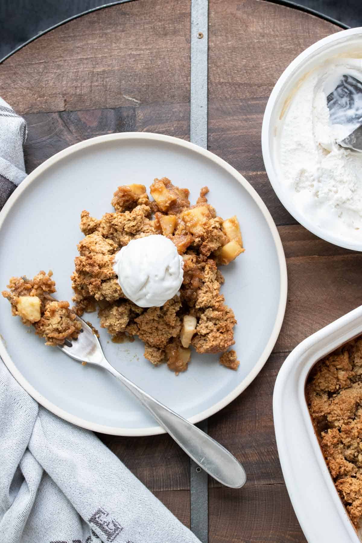 Top view of apple crisp with whipped cream on a grey plate.