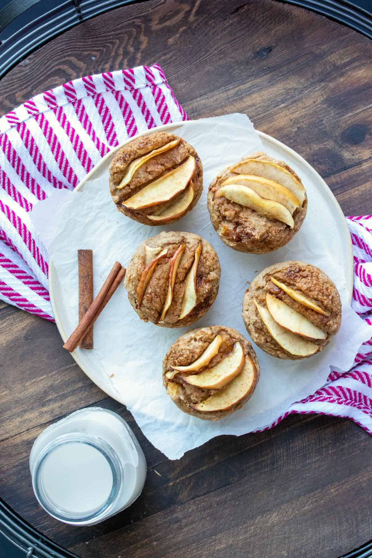 White plate with baked muffins topped with sliced apples