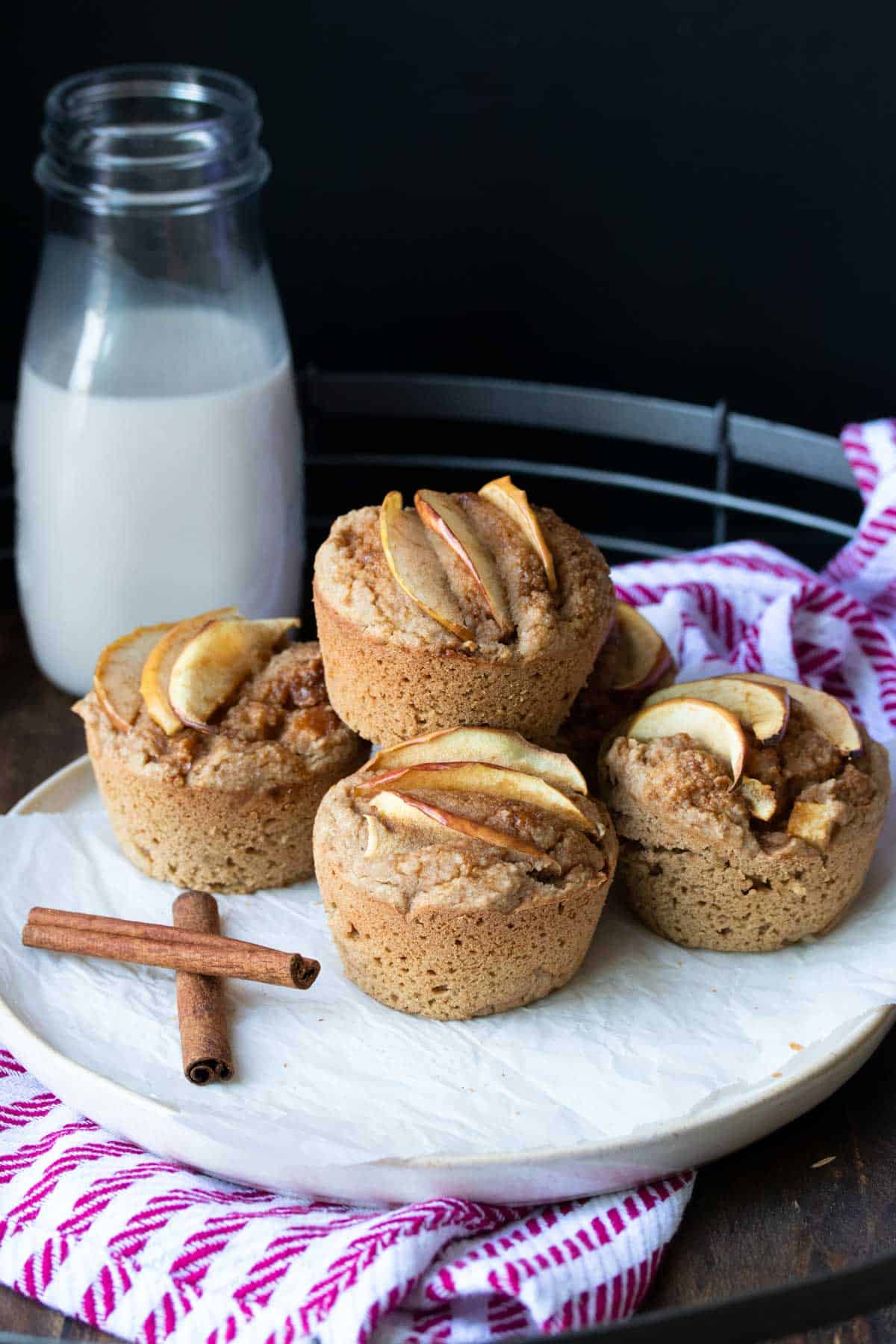 Pile of apple muffins on a piece of parchment on a plate.